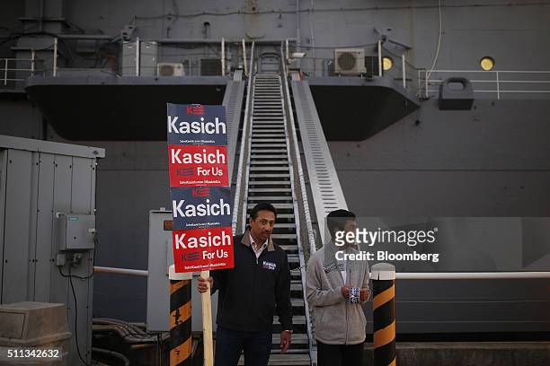 Volunteers hold campaign signs for John Kasich, governor of Ohio and 2016 Republican presidential candidate, before a campaign event at the Patriots...