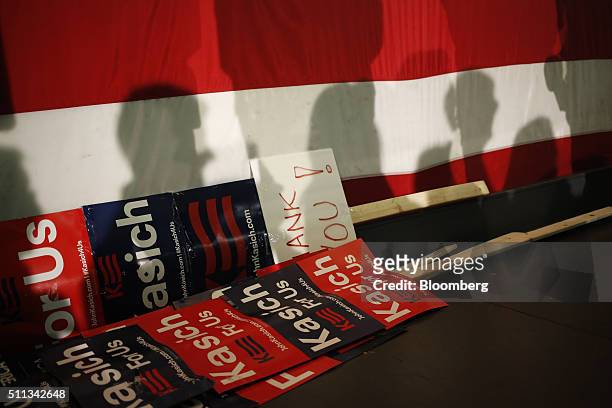 Shadows of attendees are cast on a U.S. Flag as campaign signs sit on stage during a campaign event for John Kasich, governor of Ohio and 2016...