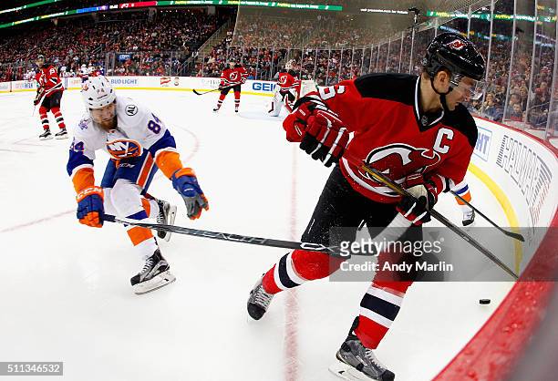 Andy Greene of the New Jersey Devils plays the puck while being stick checked by Mikhail Grabovski of the New York Islanders during the game at the...