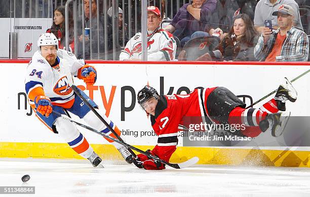 Reid Boucher of the New Jersey Devils is tripped up in the third period as Mikhail Grabovski of the New York Islanders skates for the puck at the...