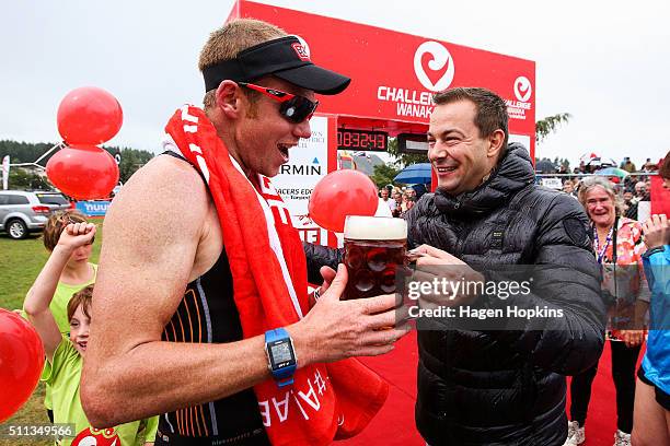 Dougal Allan of New Zealand celebrates his win with a beer from Challenge Series CEO Felix Walchshofer during 2016 Challenge Wanaka on February 20,...