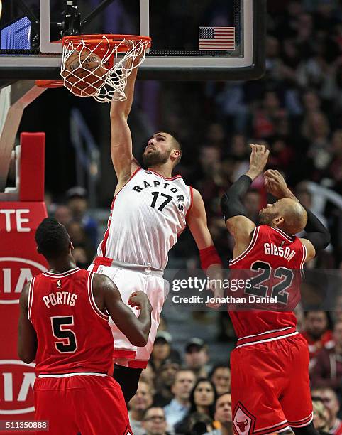 Jonas Valanciunas of the Toronto Raptors dunks over Bobby Portis and Taj Gibson of the Chicago Bulls at the United Center on February 19, 2016 in...