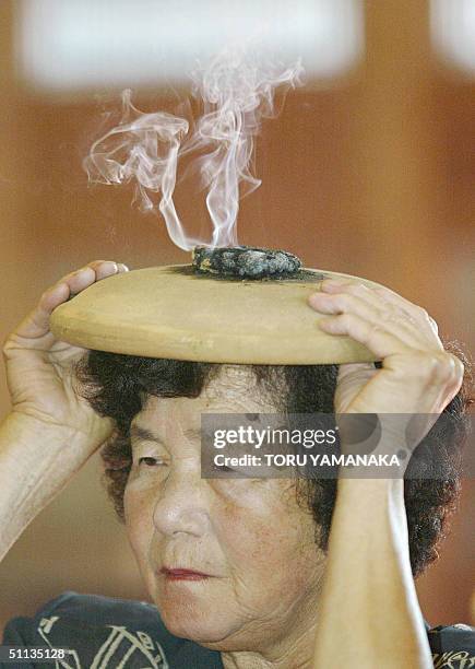 An elderly woman burns moxa atop an unglazed plate on her head in order to improve her health, at the Myoshin-ji Temple in Kawagoe, suburban Tokyo,...