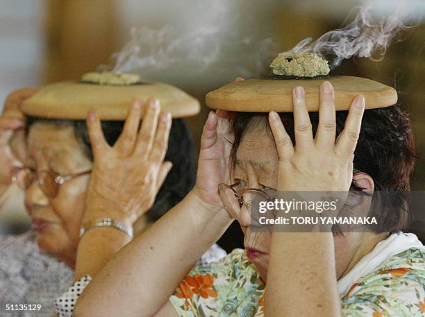 Elderly women burn moxa atop an unglazed plate on her head in order to improve her health, at the Myoshin-ji Temple in Kawagoe, suburban Tokyo, 02...