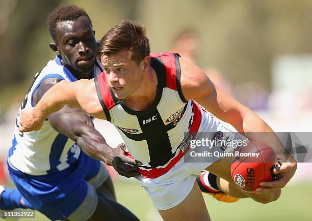 Jack Sinclair of the Saints handballs whilst being tackled by Majak Daw of the Kangaroos during the 2016 AFL NAB Challenge match between the St Kilda...