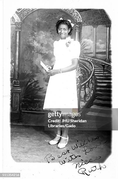 Full length portrait of young African-American woman in white knee-length dress, standing in front of fresco, 1920. .