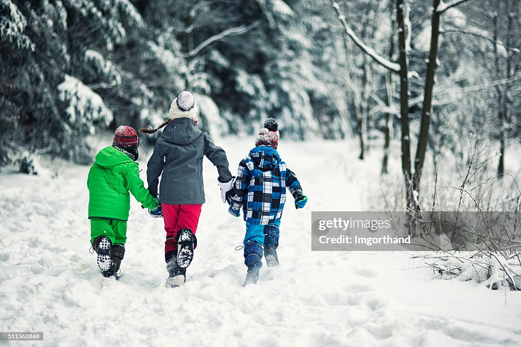 Drei Kinder Laufen im Winter Wald