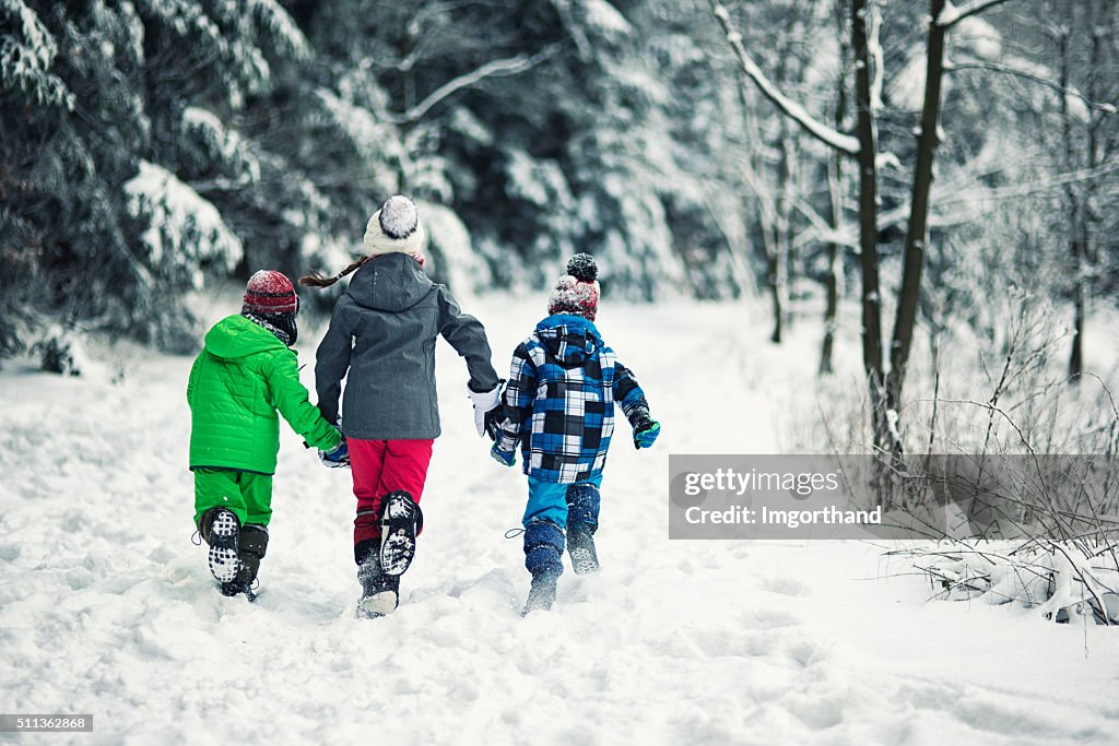 Three kids running in winter forest