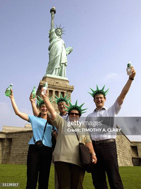 Eva, Edith , Marcus and Moritz Tannast from Switzerland raise bottles of water as they pose for a picture in front of the Statue of Liberty on...