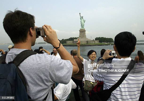 Tourists photograph the Statue of Liberty as they arrive by ferry from Manhattan to Liberty Island in New York 03 August, 2004. The Statue's pedestal...