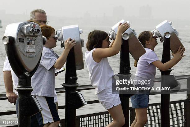 Visitors use coin operated viewing binoculars to look at the face of the Statue of Liberty on Liberty Island in New York 03 August, 2004. The...