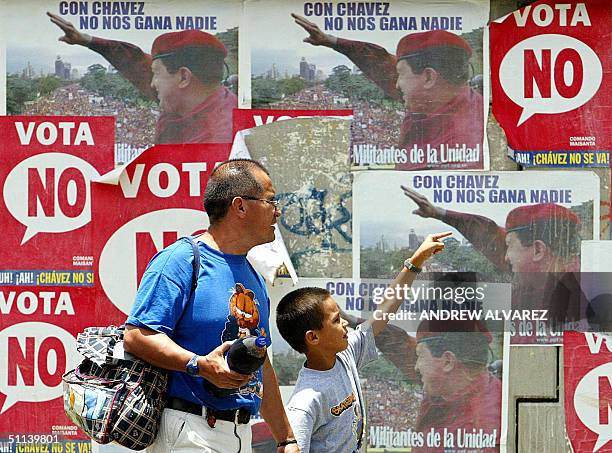 Un hombre y su hijo caminan frente a un muro con afiches promoviendo la campana a favor del mandatario venezolano Hugo Chavez, en Caracas el 03 de...