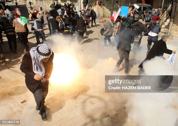 Protesters take cover from smoke and flames as Israeli soldiers fire stun grenades and tear gas during clashes following a demonstration against...