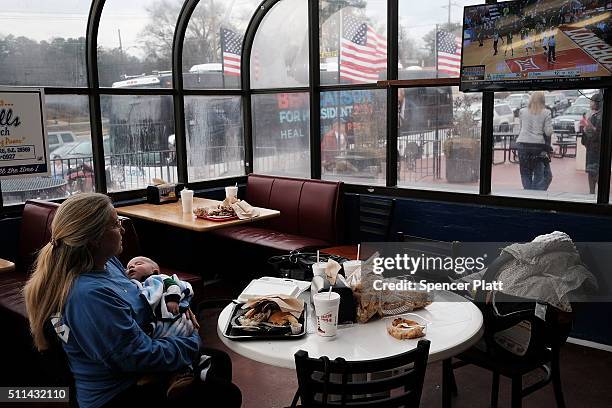 Woman with a child waits as Republican presidential candidate Ben Carson visits voters in a restaurant during the Republican presidential primary on...