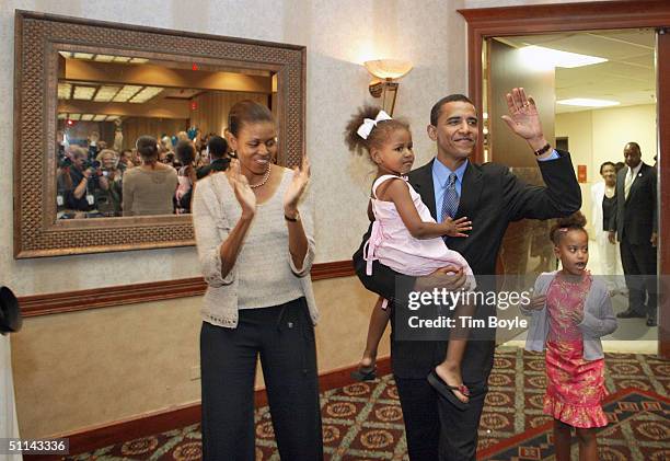 Barack Obama waves to supporters as he arrives at his 43rd birthday celebration with his wife Michelle and daughters Sasha, in his arms, and Malia...