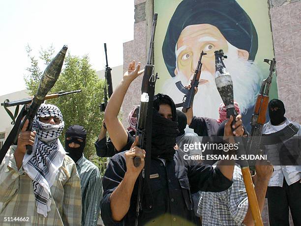 Militiamen loyal to radical Shiite cleric Moqtada Sadr pose in front of a wall decorated with a portrait of Sadr's father, Mohammed Sadeq al-Sadr, 05...