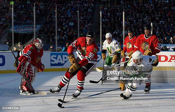 Eric Daze of the Chicago Blackhawks Alumni controls the puck against Neal Broten of the Minnesota North Stars Alumni in the first period during the...