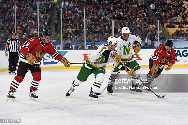 Darby Hendrickson of the Minnesota Wild Alumni pass the puck away from Troy Murray and Denis Cyr of the Chicago Blackhawks Alumni as Reed Larson of...