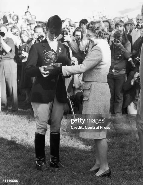 Queen Elizabeth II presents the Raleigh trophy to her daughter Princess Anne, winner of the individual European three-day event at Burghley,...