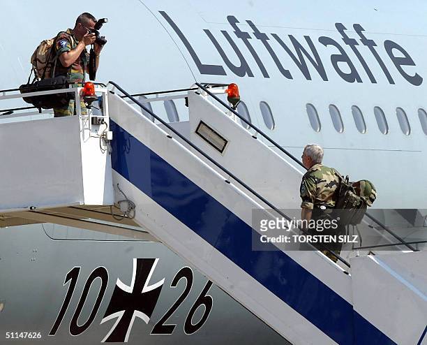 Member of the Eurocorps takes a picture of French General Jean-Louis Py as he boards an aircraft in Cologne 06 August 2004 before flying out of...