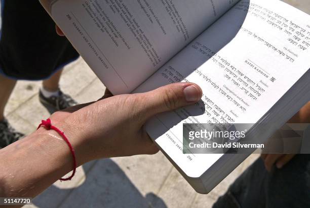 Jewish teenage girl wears her Kabbalah Red String Bracelet while praying at the Western Wall, Judaism's holiest site, August 6 in Jerusalem's Old...