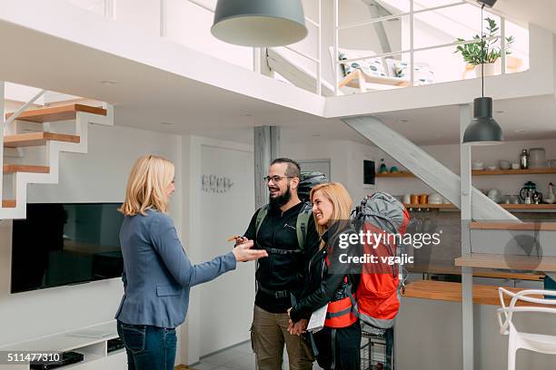 host welcomes backpackers in her apartment. - huurhuis stockfoto's en -beelden