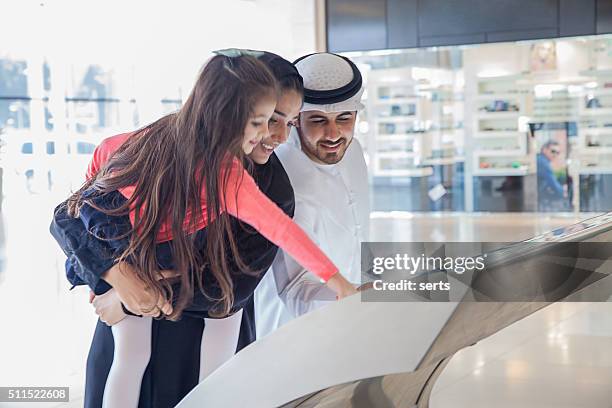 young arab family using information display at mall - merchandise booth stock pictures, royalty-free photos & images