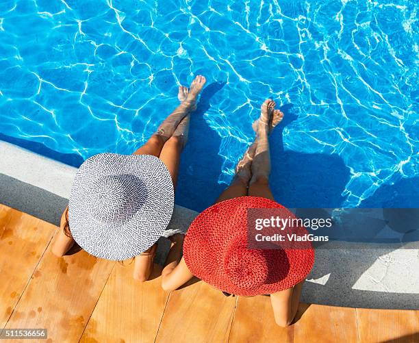 deux femme de détente dans la piscine du centre de villégiature - chapeau de soleil photos et images de collection