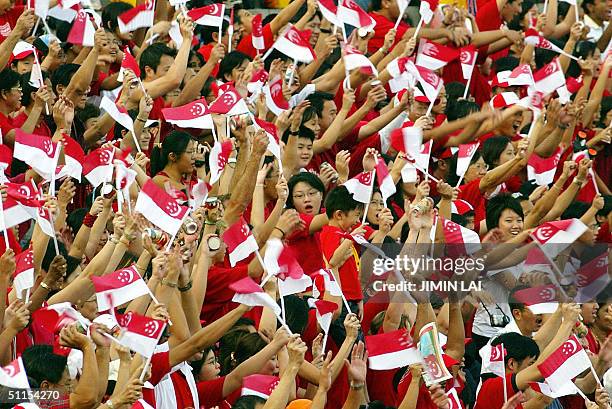 Singaporeans wave their country's national flag at the national stadium during the National Day Parade celebrations in Singapore, 09 August 2004....