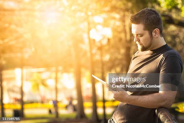 young man using tablet in a park - orlando florida city stock pictures, royalty-free photos & images