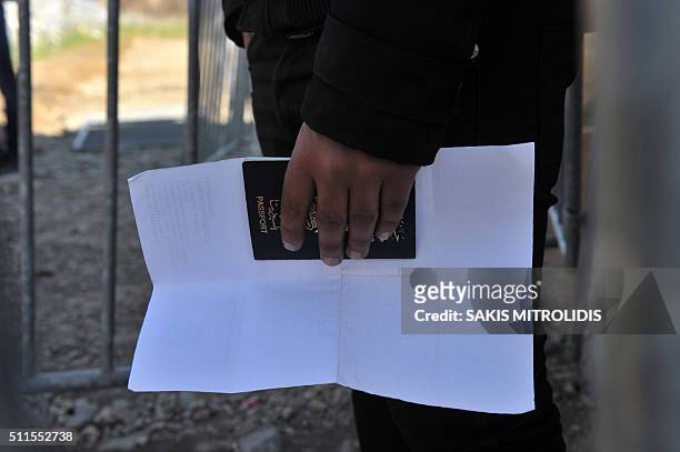Man holds his passport as he waits with other migrants and refugees to cross the Greek-Macedonian border near the village of Idomeni, in northern...
