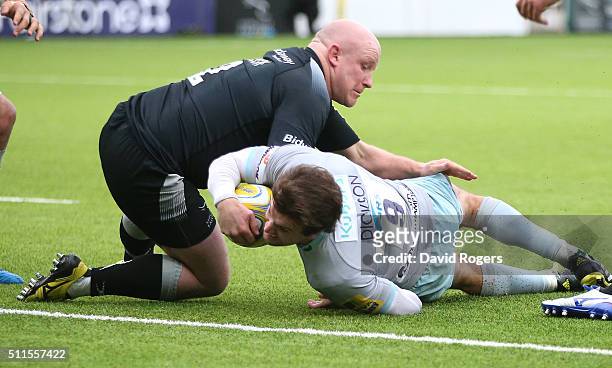 Lee Dickson of Northampton dives over for a try despite the attention of Scott Lawson during the Aviva Premiership match between Newcastle Falcons...