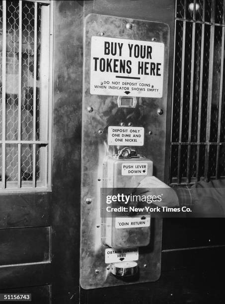 Male hand depresses a lever on the first subway token vending machine at Change Booth 504 at Sixth Avenue and 40th Street in New York, April 19,...