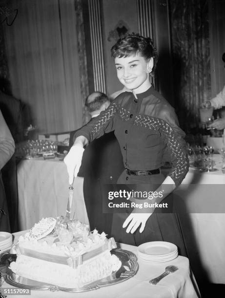 Belgian-born actress Audrey Hepburn cuts into a 'Welcome Home' cake during a reception at Claridges Hotel, 21st May 1953. She has just arrived back...