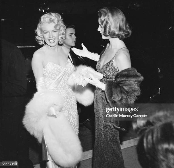 American actress Marilyn Monroe laughs with fellow actress Lauren Bacall at the premiere of Jean Negulesco's film 'How to Marry a Millionaire,' in...