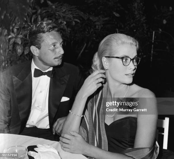 Costume and fashion designer Oleg Cassini sits at a table with American actress Grace Kelly at a party given by Hollywood gossip columnist Louella...