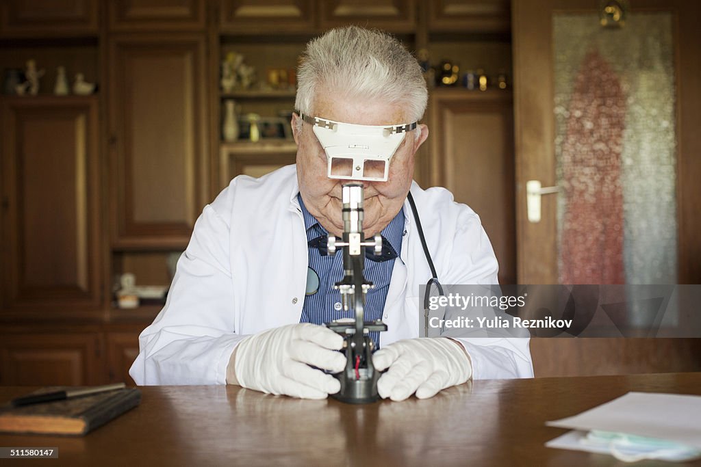 Senior man looking through microscope