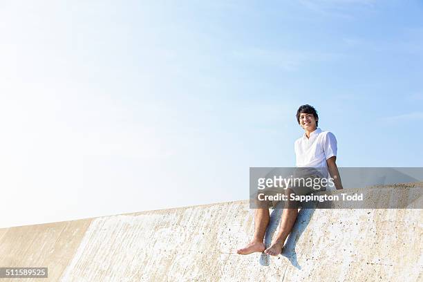 man sitting on breakwater - groyne ストックフォトと画像