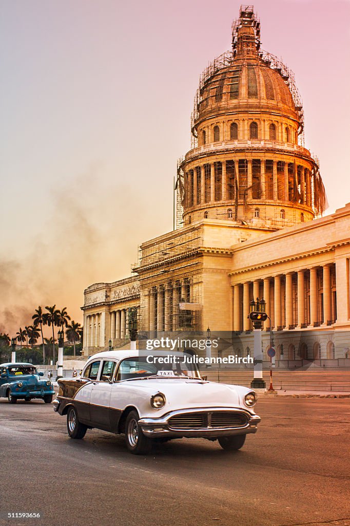 Vintage cars outside Capitolio at dusk