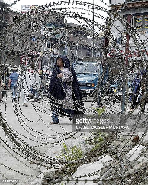 An unidentified Indian Kashmiri woman walks by a barbed-wire fence during a stop and search operations in Srinagar's main commercial hub Lal Chowk,...