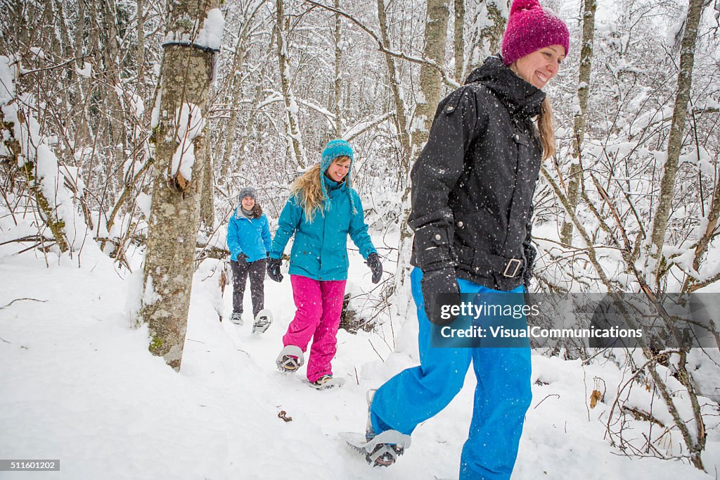 Eine Gruppe von Freundinnen Schneeschuhwanderungen im Wald.