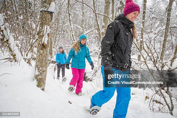 eine gruppe von freundinnen schneeschuhwanderungen im wald. - schneeschuh stock-fotos und bilder