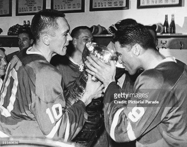Hockey players George Armstrong , Andy Bathgate , and other members of the victorious Toronto Maple Leafs drink from the Stanley Cup, the National...