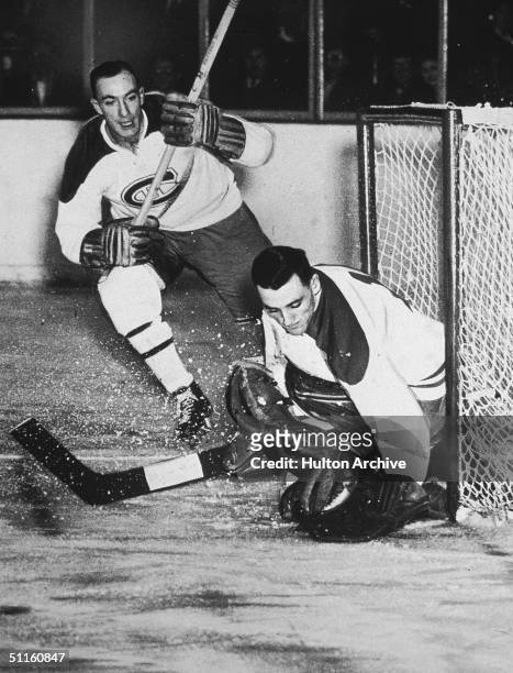 Montreal Canadiens goalkeeper Jacques Plante makes a save as teammate Bud McPherson watches, stick raised, 1954.