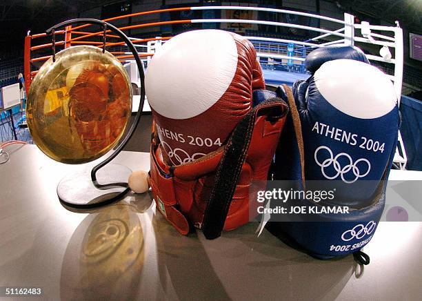Boxing gloves and a ringside bell stand before the official boxing ring at Peristeri Olympic Boxing Center in Athens on 12 August 2004, one day...