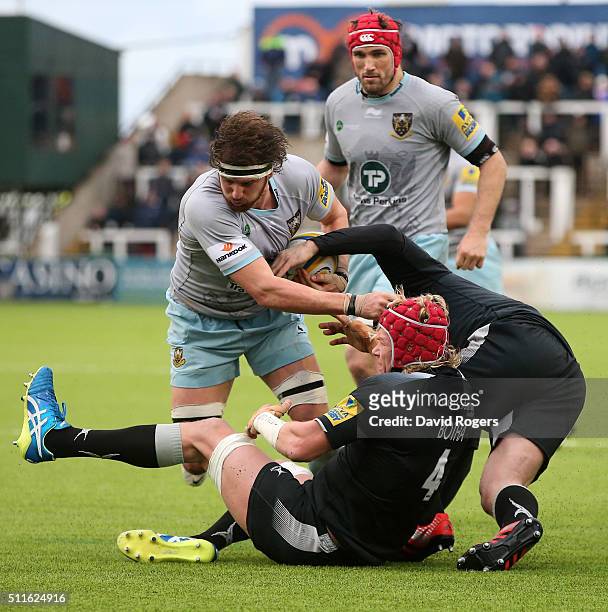 Tom Wood of Northampton is tackled by Mouritz Botha during the Aviva Premiership match between Newcastle Falcons and Northampton Saints at Kingston...
