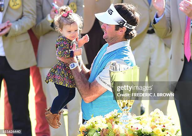 Bubba Watson of the United States lifts his daughter Dakota before the championship trophy on the final day at the 2016 Northern Trust Open on...