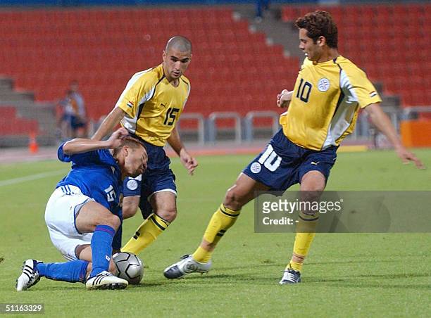 Yuhei Tokunaga of Japan falls before Paraguayan players Diego Figueredo and Ernesto Cristaldo during their 2004 Olympic soccer match 12 August 2004...