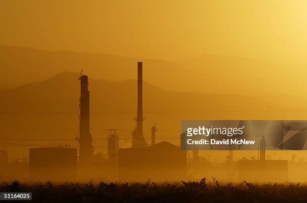 The sun rises over the Kern Oil and Refining Co. Refinery on August 12, 2004 near the town of Lamont, southeast of Bakersfield, California. High...