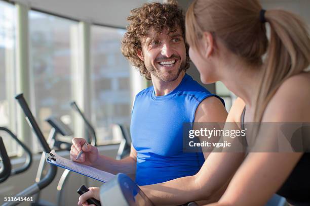 woman in a gym with personal trainer. - happy caucasian woman on elliptical trainer at gym stock pictures, royalty-free photos & images